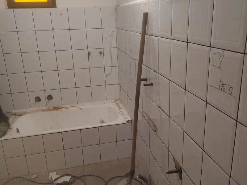 Fürdőszoba a felújítás előtt, régi burkolattal a fali WC és a törölközőszárító oldalán