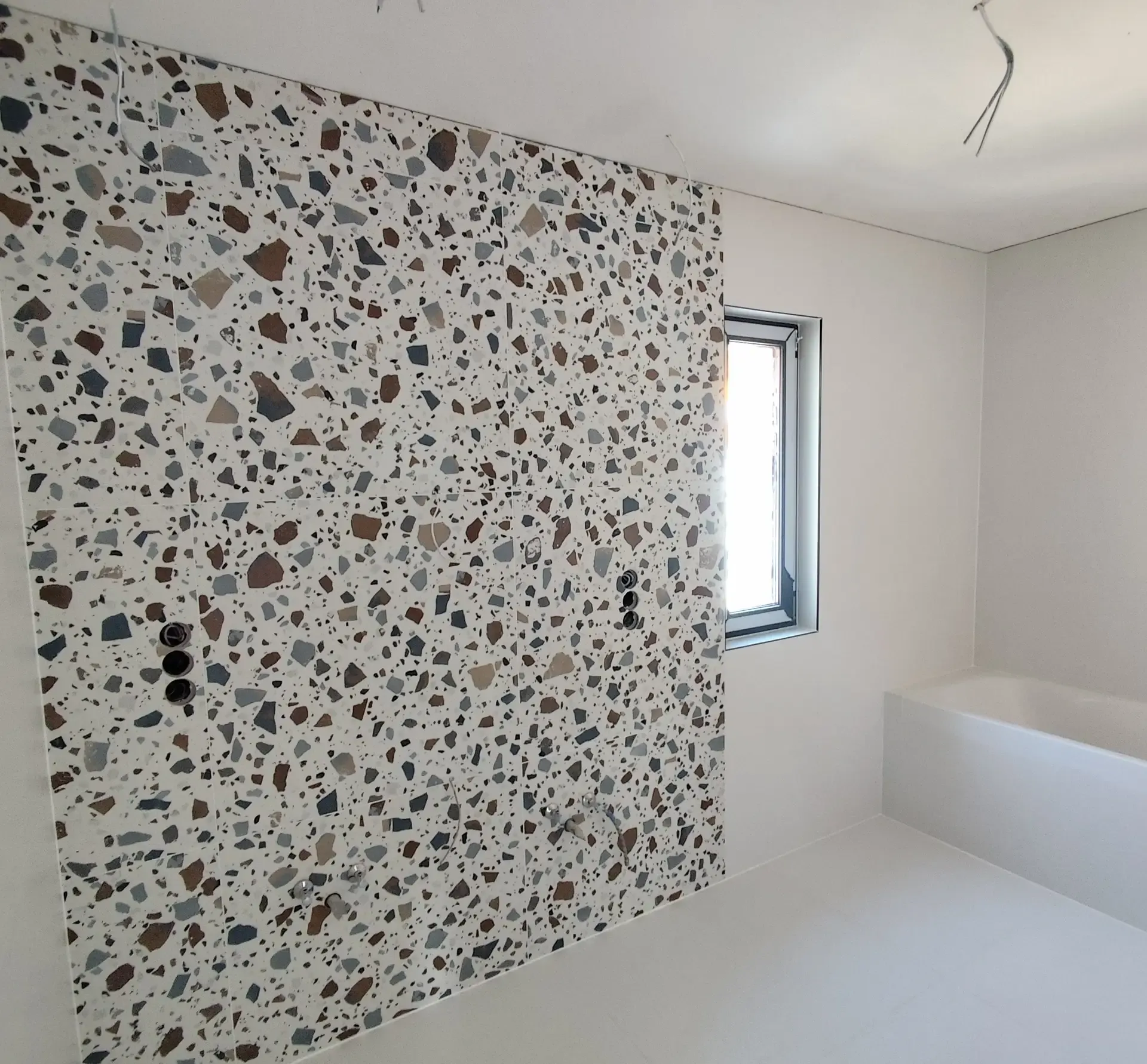 Terrazzo mintás óriáslapos falburkolat fürdőszobában, összefüggő felülettel
