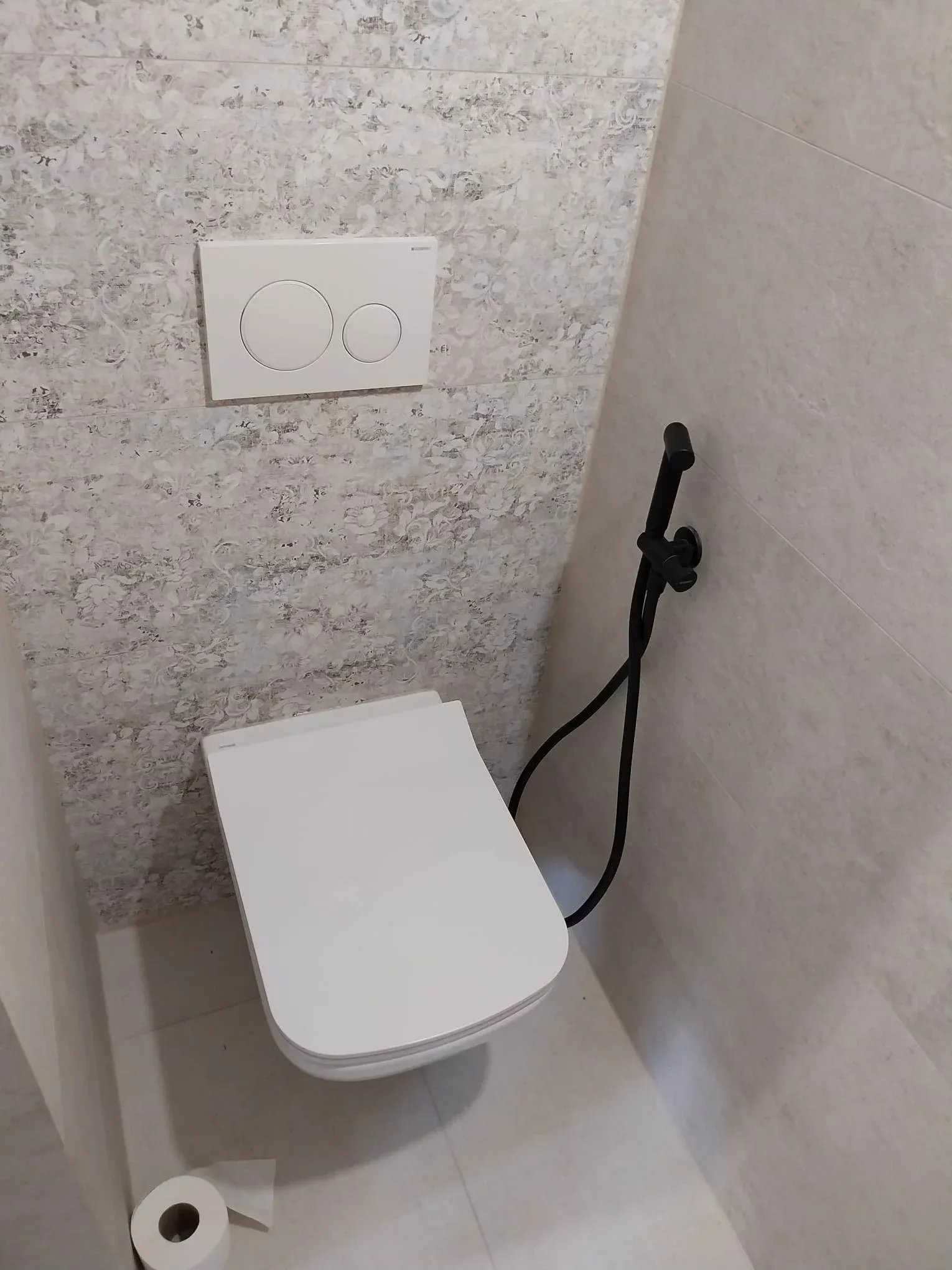 WC világos kőhatású falburkolattal, fali WC-vel és fekete csapteleppel